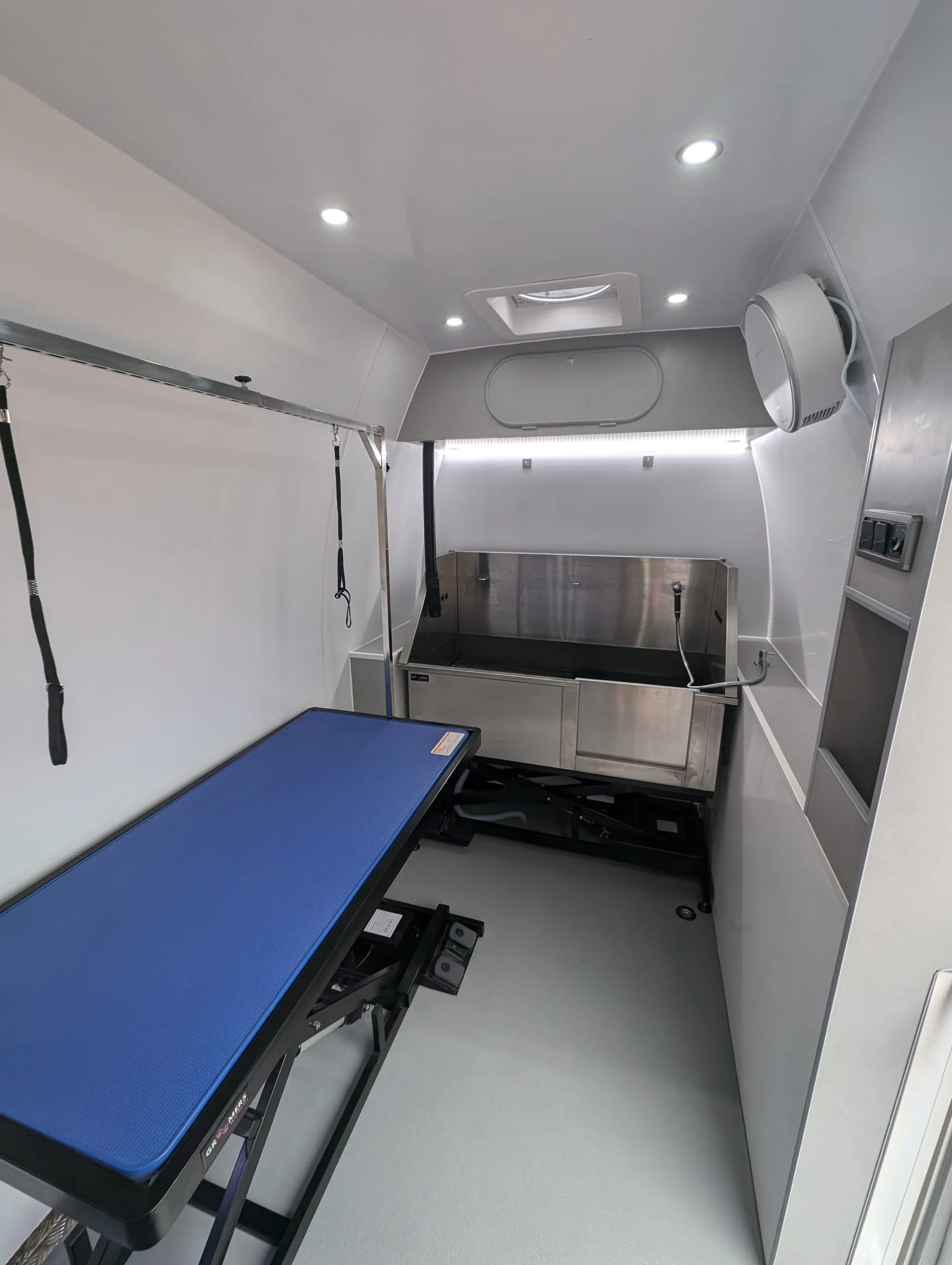 Interior of a dog grooming van with height-adjustable grooming table
